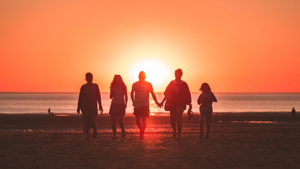 family walking on beach at sunset